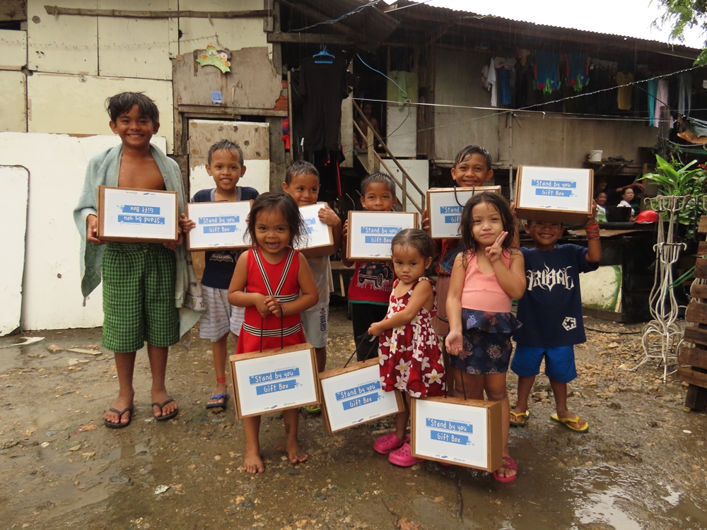 쓰레기장 이주민 마을에 거주중인 빈곤아동들이 선물받은 태양광랜턴과 학용품세트를 들고 기념촬영을 하고 있다.JPG